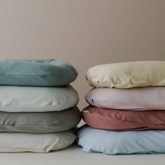 four pillows stacked on top of each other in different colors and sizes, with the covers folded down