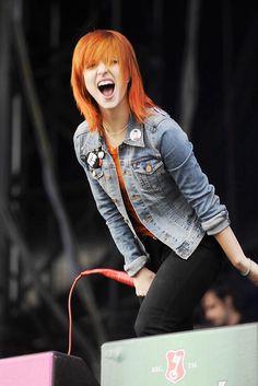 a woman with red hair is on stage and has her mouth open as she sings