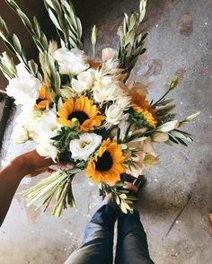 a person holding a bouquet of sunflowers and tulips