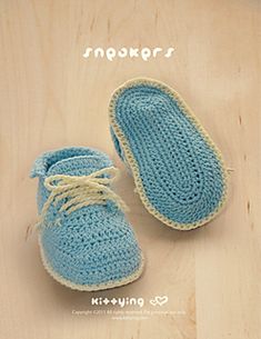 a pair of blue crocheted baby shoes sitting on top of a wooden floor