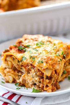 a white plate topped with lasagna casserole next to a red and white towel