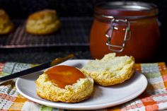 two biscuits on a plate next to a jar of jam