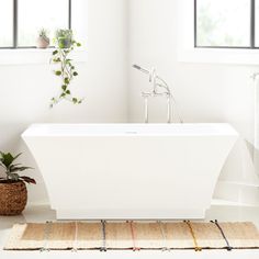 a white bath tub sitting in a bathroom next to a window with potted plants