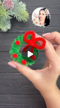 a person holding up a christmas wreath made out of yarn and felt with an image of a woman's face in the background