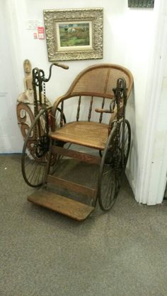 an old fashioned rocking chair next to a wall with a painting on the wall behind it