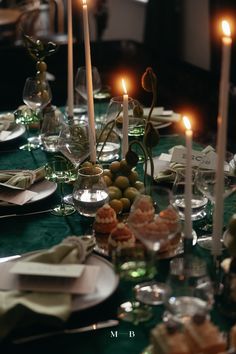 the table is set with candles, plates and napkins for an elegant dinner party