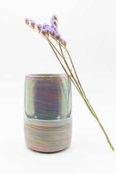 a vase with some flowers in it on a white surface and one flower is sticking out of the cup