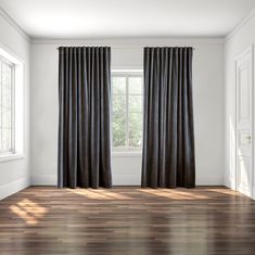 an empty room with wood floors and black curtains