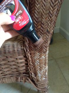 a person is holding a tube of deodorant on a wicker chair