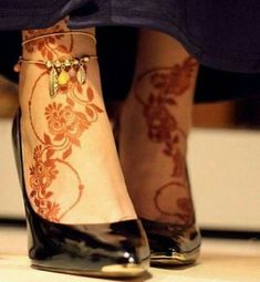 a woman's legs with henna tattoos and high heels