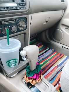 a starbucks cup sitting on top of a car dashboard next to a drink dispenser