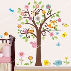 a baby's room with a tree and wall decals in the shape of animals