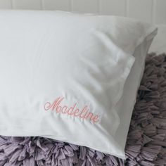 a white pillow with the word madeline on it sitting on a purple bed spread