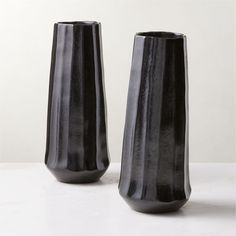 two black vases sitting next to each other on a table