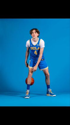 a young man holding a basketball while standing in front of a blue background