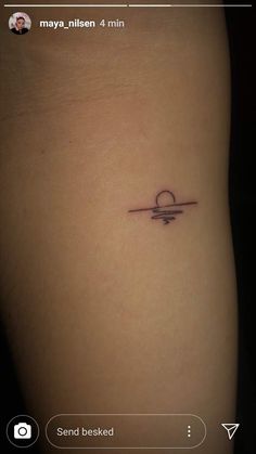 a small tattoo on the back of a woman's thigh, with an arrow in the middle