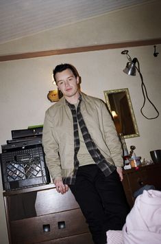 a man sitting on top of a wooden dresser