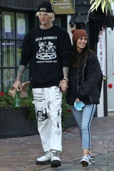 a man and woman walking down the street holding hands