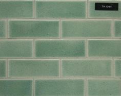 a green brick wall with a black sign on the side that says tim grey in english