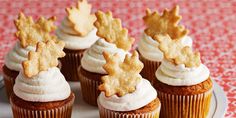 small cupcakes with white frosting and gold leaf decorations on top are sitting on a plate