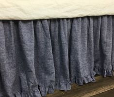 there is a bed that has been made with blue linens and ruffled bedskirts