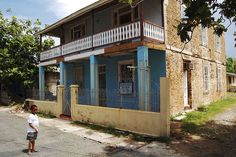 a young boy standing in front of a blue and white building with balconies