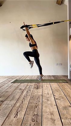 a woman is doing yoga on a mat with a resistance band attached to her back