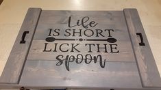 a wooden sign that says life is short, lick the spoon on top of it