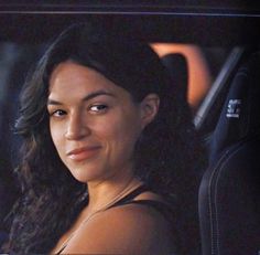 a woman sitting in the back seat of a car with her hand on her hip