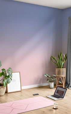 a laptop computer sitting on top of a wooden floor next to a potted plant