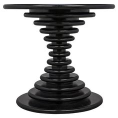 a black table with an oval glass top and spiral design on the base, against a white background