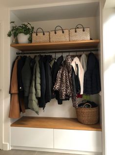 an organized closet with clothes and bags on the shelves, including coat hangers and baskets