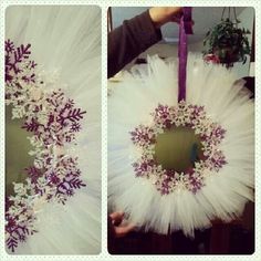 the wreath is decorated with white tulle and purple trimmings, while being held by someone's hand