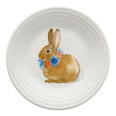 a white bowl with a brown rabbit painted on it's side and blue flowers in its mouth