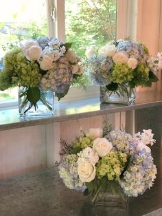 three vases with flowers are sitting on a counter