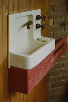 a white sink sitting on top of a wooden counter next to a brick wall and door