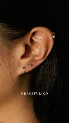 a woman's ear with two piercings on it