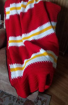 a red and yellow blanket sitting on top of a couch next to a white chair