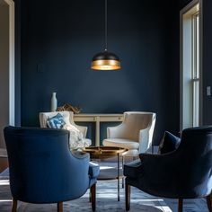 two chairs and a table in a room with dark blue walls, one chair is upholstered