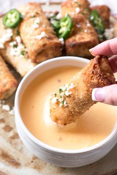 a person dipping some food into a small white bowl on a plate with bread sticks