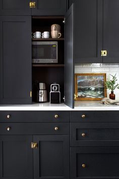 a kitchen with black cabinets and white counter tops, gold knobs on the doors