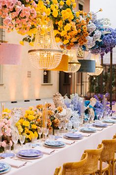 the table is set with many different colored flowers and place settings for dinner guests to eat