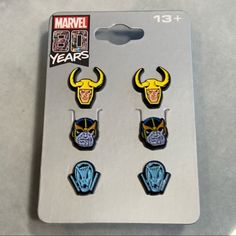 three magnets with the faces of wolverine and iron man on them, sitting in front of a card