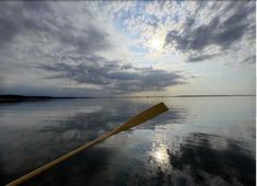 a long wooden oar sitting on top of a body of water under a cloudy sky