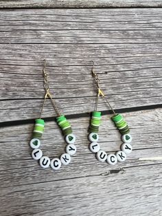 green and white beaded hoop earrings with the word luck written on each earring