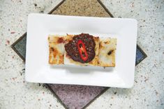 a white plate topped with food on top of a tile floor next to a tiled floor