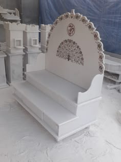 a white bench with intricate designs on it's back and sides, sitting in the middle of an unfinished room