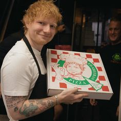 a man holding up a pizza box with an image of a monkey on it's side