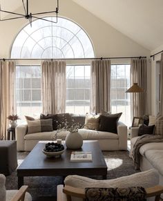 a living room filled with lots of furniture and large arched windows in the wall behind it