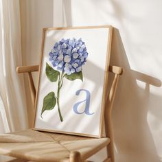 a blue hydrangea flower sitting on top of a wooden chair next to a window